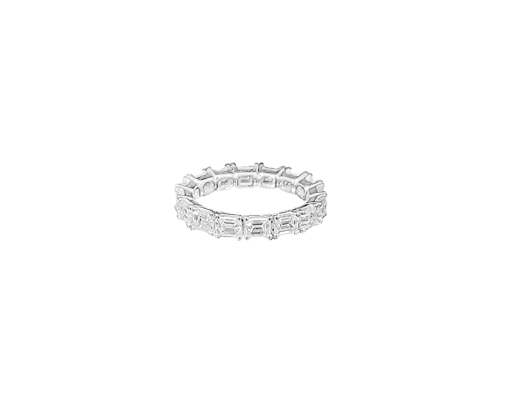 An emerald eternity band featuring vivid green emerald gemstones encircling the entire band, set against a clean, white background, highlighting the brilliance and elegance of the jewelry piece.