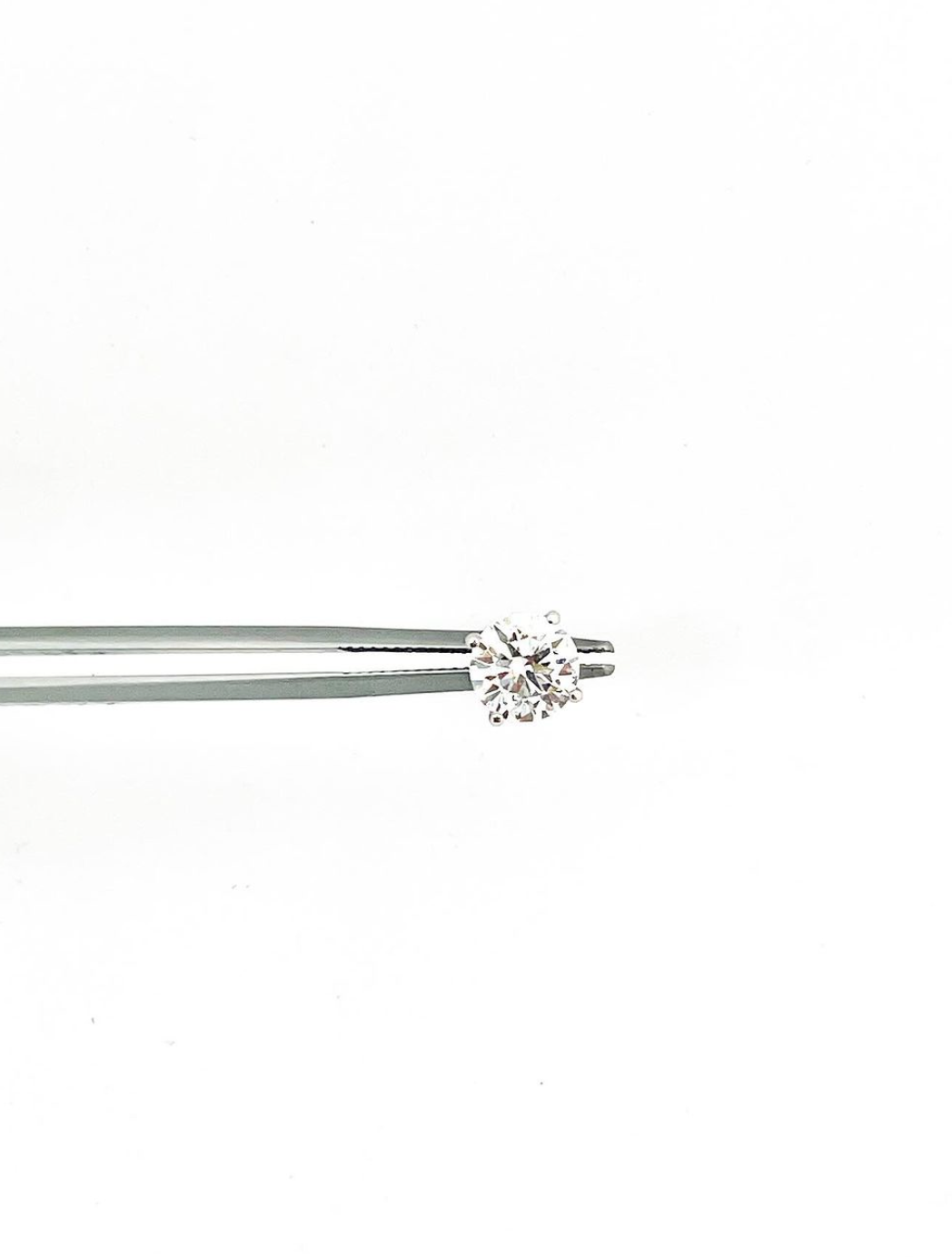 Diamond held by tweezers against white text 