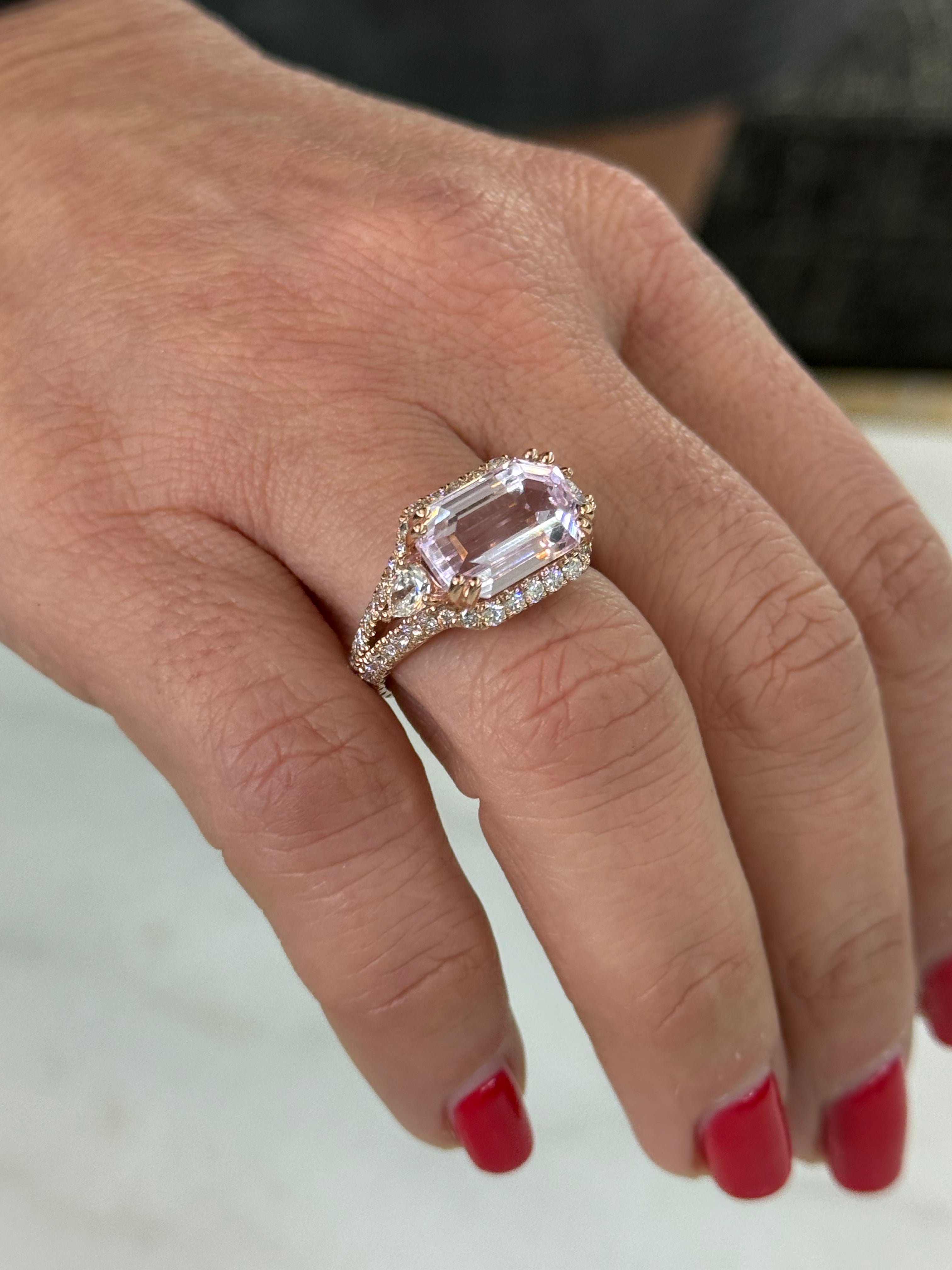 Close-up of a hand wearing a pink gemstone ring on a neutral background