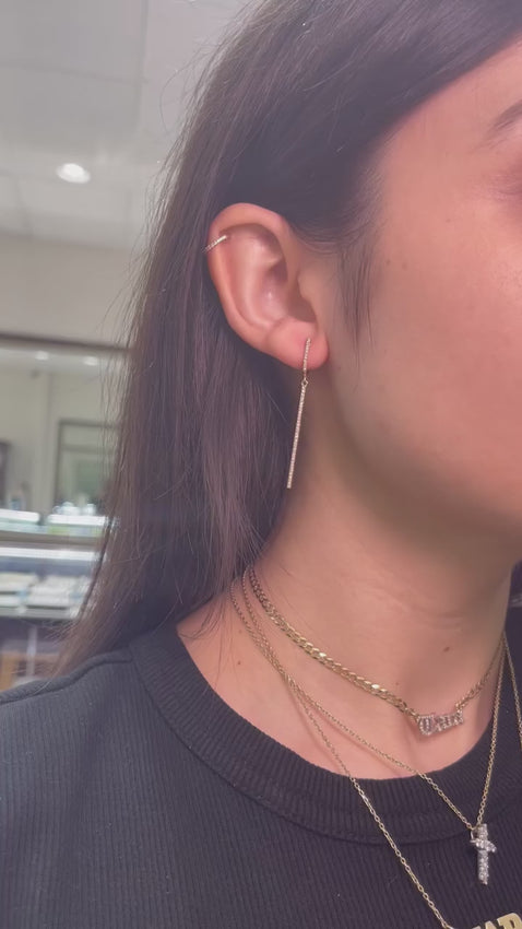 Video showing model wearing diamond huggie bar dangle earrings. 