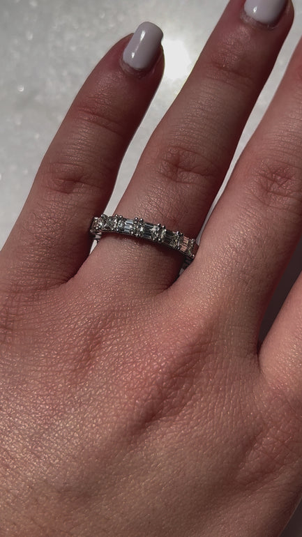 A video featuring a model elegantly displaying an emerald diamond eternity band, the sparkling emerald-cut diamonds intricately set around the band, catching the light with mesmerizing brilliance as the model's hand moves gracefully, showcasing the luxurious and timeless beauty of the jewelry piece against a subtle background.