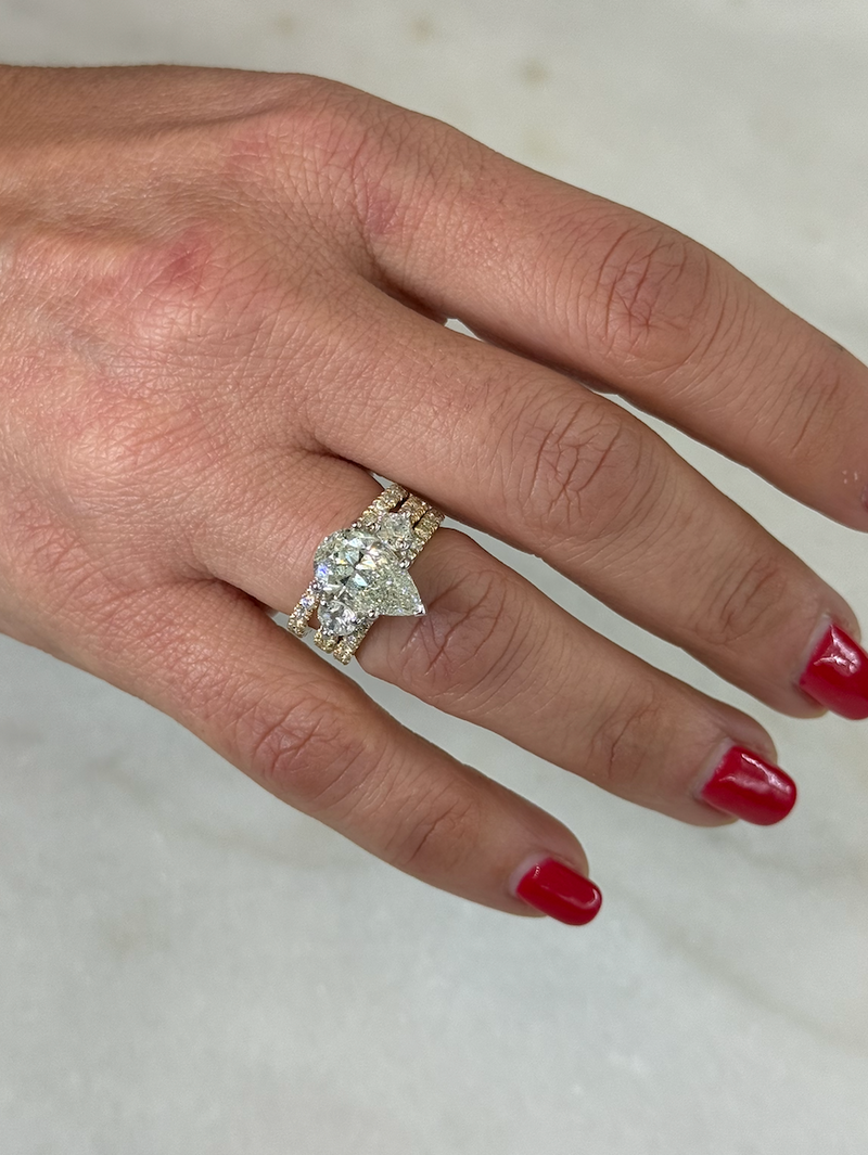 Hand wearing a diamond ring with red nail polish on a neutral background